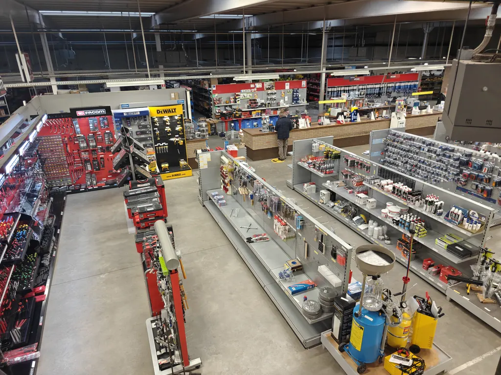 Zicht over de winkelrekken naar de toonbank van Autoshop Coremans